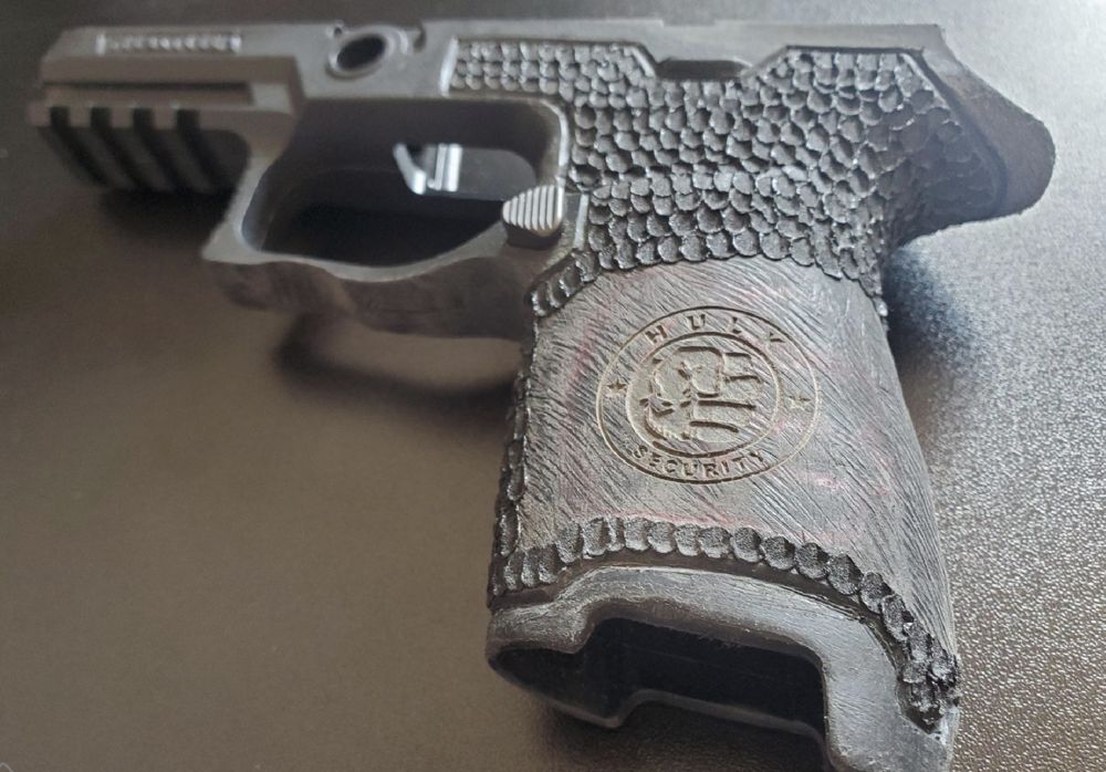 Pistol frame with scale-pattern texturing and an engraved company logo on the grip
